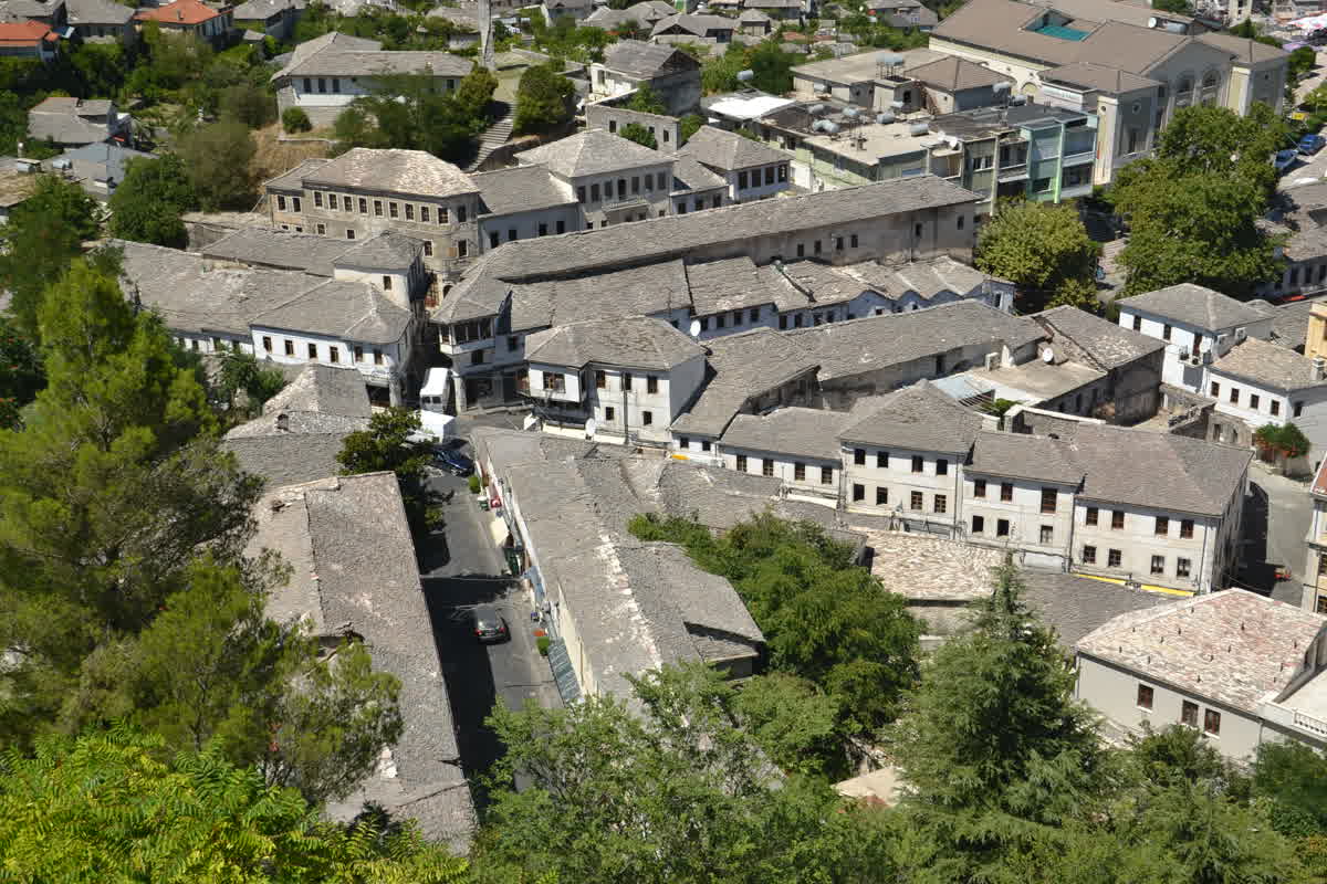 Stone-slab rooftops of Gjirokastër viewed from above, densely packed down the hillside