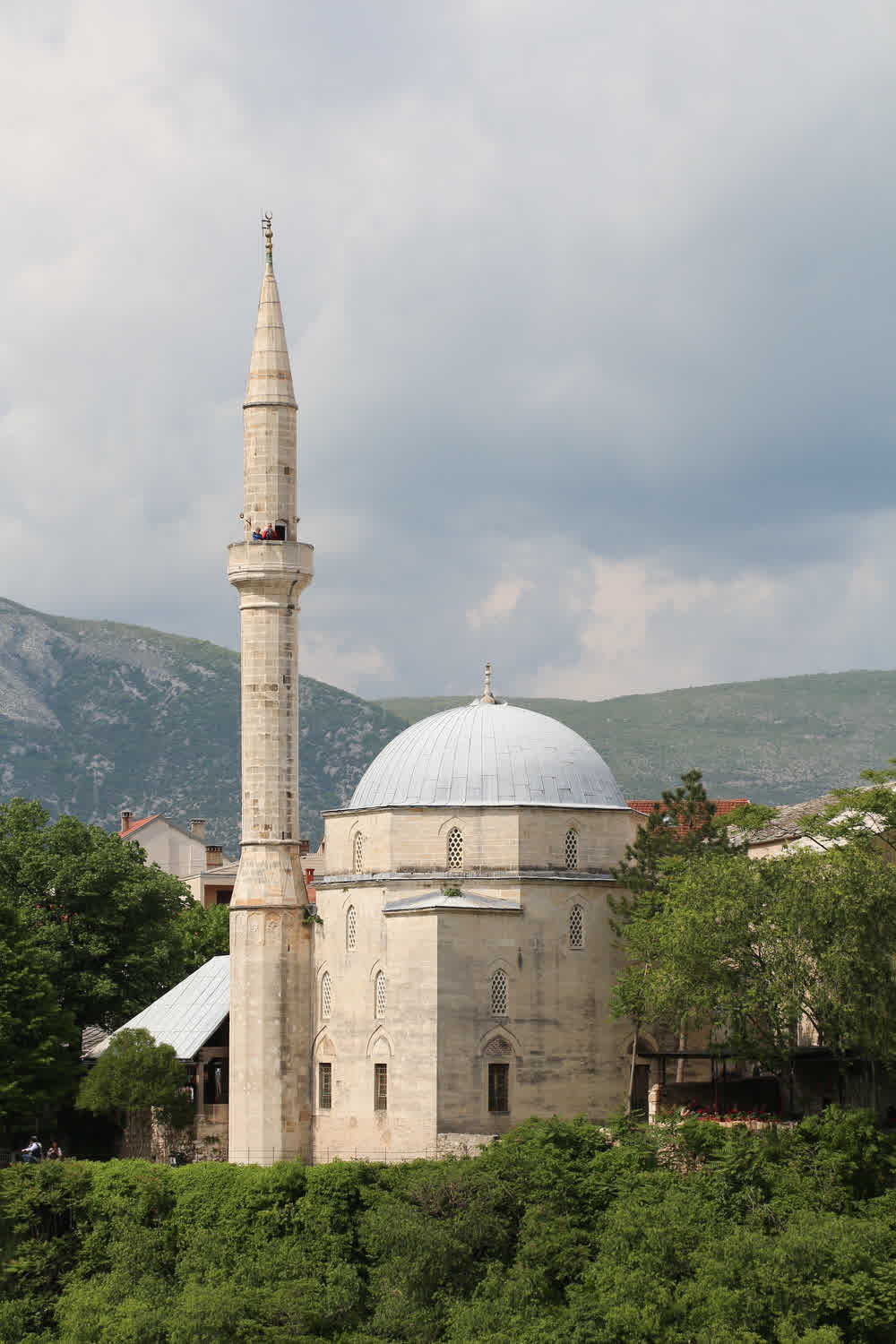 The Koski Mehmed Pasha Mosque in Mostar, its Ottoman minaret rising above stone walls along the Neretva River