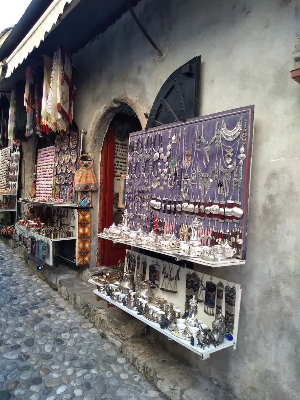 The cobblestone Kujundziluk bazaar street in Mostar, lined with traditional craft stalls beneath Ottoman-era buildings